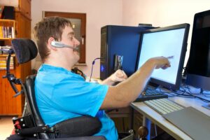 A man in a wheelchair, using a computer.