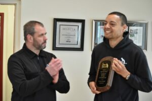 two men. One clapping for the other because he won an award.