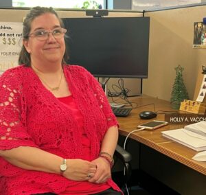 A women in a red shirt sitting at a desk.