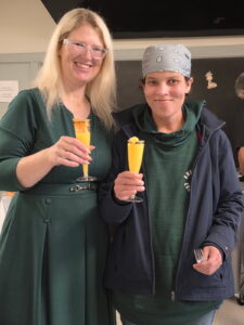 Two women standing together and smiling.